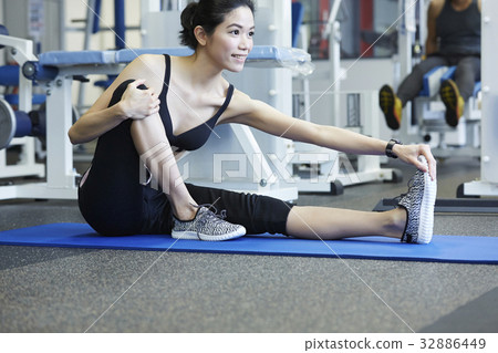 A woman is sitting and warming up at a fitness room 32886449