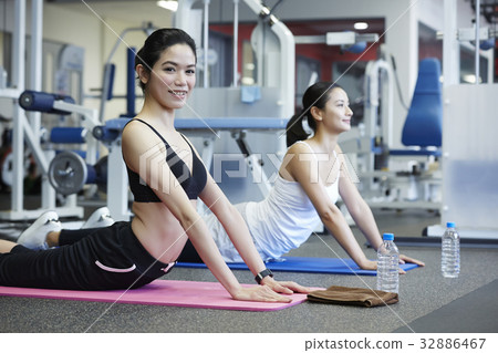 A girl and her friend are practising at a fitness club A girl and her friend are practising at a fitness club 32886467