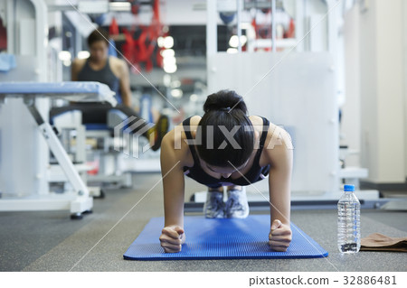 A woman is doing a plank at a sporting club 32886481
