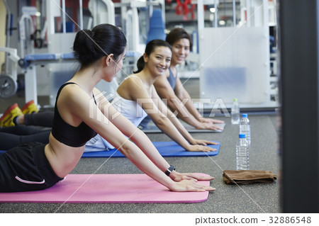 three people are exercising and smiling together in gym 32886548