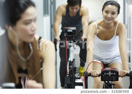 Two women are chatting together when riding bike in the fitness club 32886569