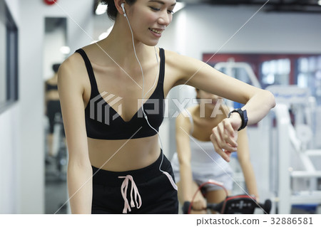 Woman is watching her watch while riding bike in fitness club. Woman is watching her watch while riding bike in fitness club. 32886581