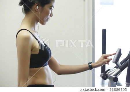 Woman wearing earphone is touching to adjust the speed of treadmill 32886595