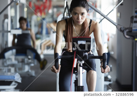 A slim and heathy woman is riding bicycle in the fitness club 32886596