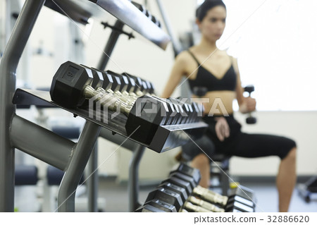 a photo of many dumbbels on a shelf next to a fit woman lifting a photo of many dumbbels on a shelf next to a fit woman lifting 32886620