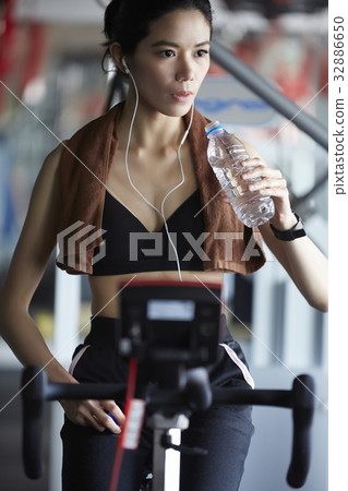A girl is taking a break after doing exercise and drinking water at fitness center A girl is taking a break after doing exercise and drinking water at fitness center 32886650
