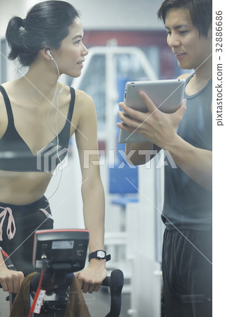 A woman is listening and looking at a man at fitness center 32886686