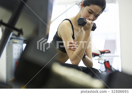 A woman is doing exercise withdumbbell at fitness center A woman is doing exercise withdumbbell at fitness center 32886691
