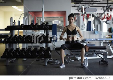 a photo of a woman doing gymnastics while sitting at a gym. 32886802