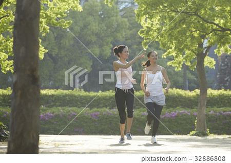 a photo of a woman pointing at someting for her friend while jogging. 32886808