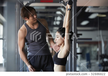 a photo of a man guiding a woman working out at a fitness center 32886822
