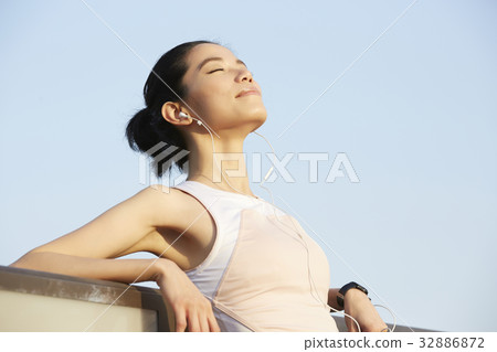 a portrait of a girl wearing earphones, breathing and relaxing outdoors. a portrait of a girl wearing earphones, breathing and relaxing outdoors. 32886872