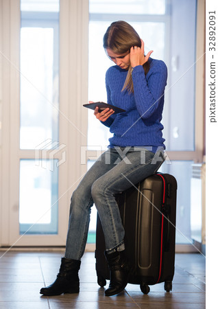 Woman with suitcase and tablet after traveling at Woman with suitcase and tablet after traveling at 32892091