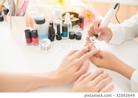 salon manicurist using electric nail drill 32892649