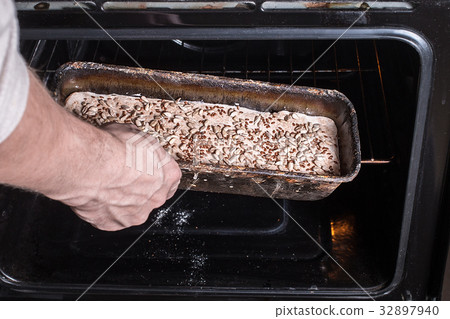 Man puts the bread in the oven Man puts the bread in the oven 32897940