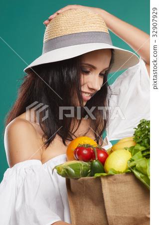 woman holding a grocery bag full of fresh and healthy food isolated on green background woman holding a grocery bag full of fresh and healthy food isolated on green background 32907929