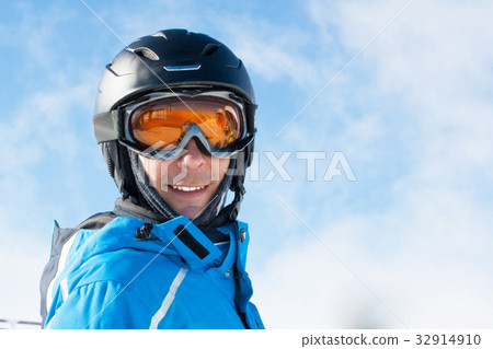 Smiling man in the blue skiing jacket, helmet and 32914910