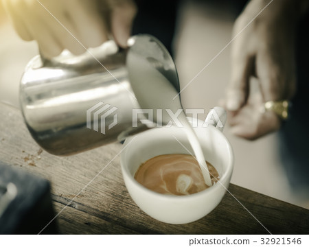 Coffee maker pouring the milk for make latte art Coffee maker pouring the milk for make latte art 32921546