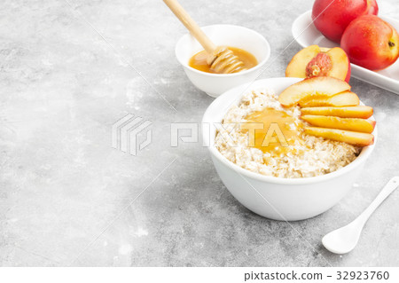 Oatmeal with nectarine, honey on a gray background Oatmeal with nectarine, honey on a gray background 32923760