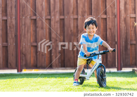 Boy 3 years old home garden kick bike exercise 32930742