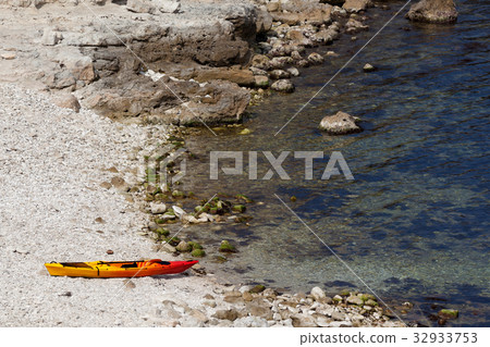 Orange kayak on pebbly beach of sea coast 32933753