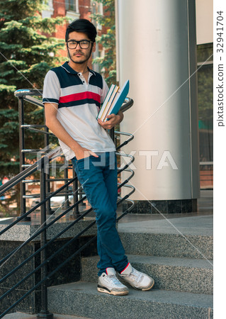 trendy guy stands on the street and holding a book trendy guy stands on the street and holding a book 32941704