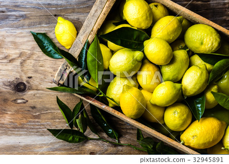 Box of lemons with fresh leaves on wooden 32945891