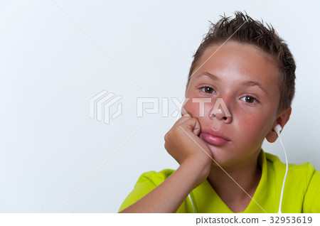 Tween boy wearing earphones looking at the camera Tween boy wearing earphones looking at the camera 32953619