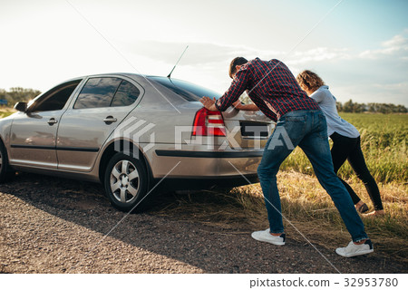 Man and woman pushing a broken car, back view Man and woman pushing a broken car, back view 32953780