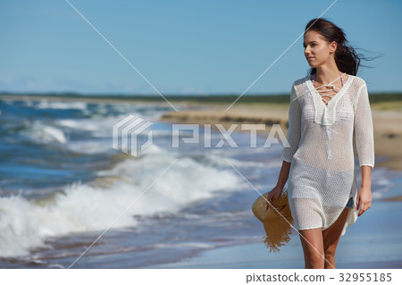 Young woman walking on white sand to beautiful beach, Baltic Sea, Poland Young woman walking on white sand to beautiful beach, Baltic Sea, Poland 32955185