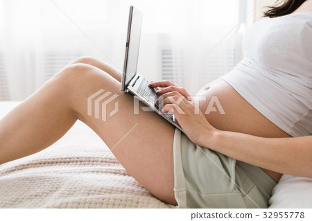 Pregnant woman with laptop in bed 32955778