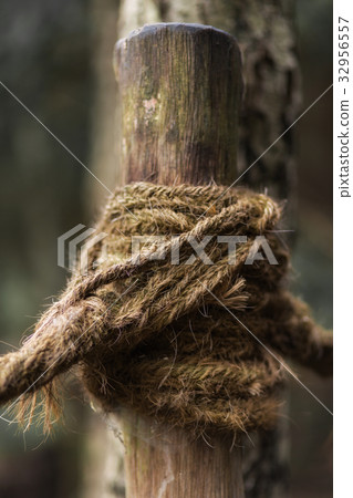 A knot of rope around a wooden post 32956557