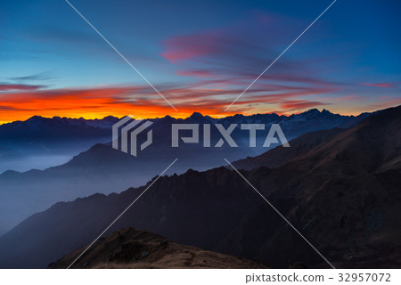 Colorful sunlight behind majestic mountain peaks Colorful sunlight behind majestic mountain peaks 32957072