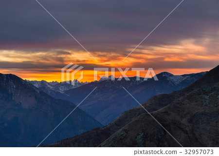 Colorful sunlight behind majestic mountain peaks Colorful sunlight behind majestic mountain peaks 32957073