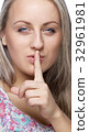a girl holds a finger to lips gesture silently 32961981