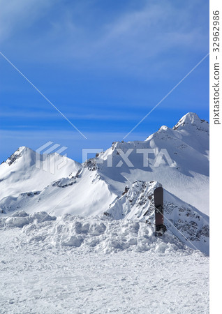 Snowboard against the snowy mountains 32962986