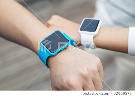 Couple comparing time on smart watch with other Couple comparing time on smart watch with other 32969575