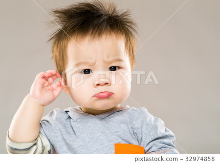 Confused baby boy hand touch ear 32974858