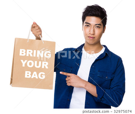 Asian mixed Indian man finger point to shopping bag for showing phrase of bring your bag Asian mixed Indian man finger point to shopping bag for showing phrase of bring your bag 32975074