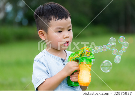 Little boy use of the bubble blower 32975957