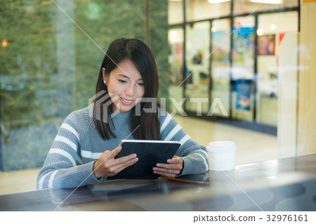 Asian woman look at tablet pc in cafe Asian woman look at tablet pc in cafe 32976161