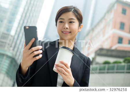 Business woman use of cellphone and holding a coffee Business woman use of cellphone and holding a coffee 32976258