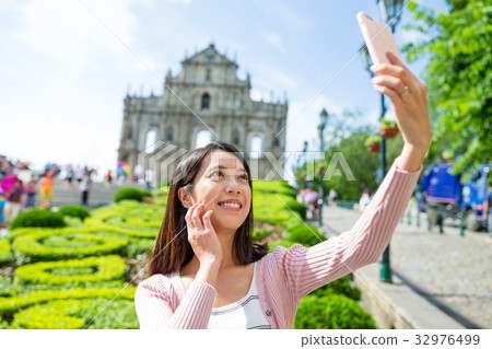 Woman taking photo by smart phone in Macau city Woman taking photo by smart phone in Macau city 32976499