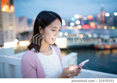 Woman sending sms on cellphone at night Woman sending sms on cellphone at night 32976501