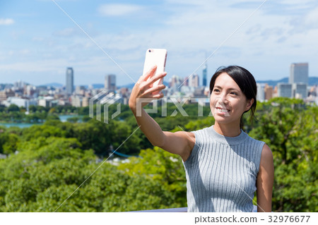 Woman taking selfie by mobile phone in fukuoka city 32976677