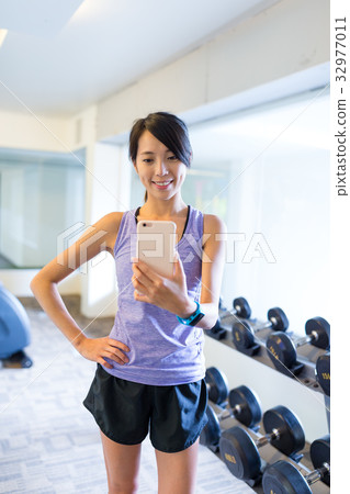 Woman taking selfie in front of mirror in gym 32977011