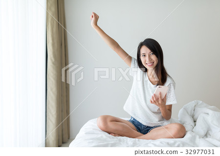 Thrilled woman shopping on cellphone at home 32977031