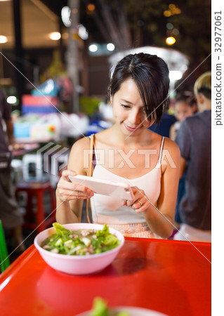 Woman taking photo on her food in outdoor market in Bangkok city 32977061