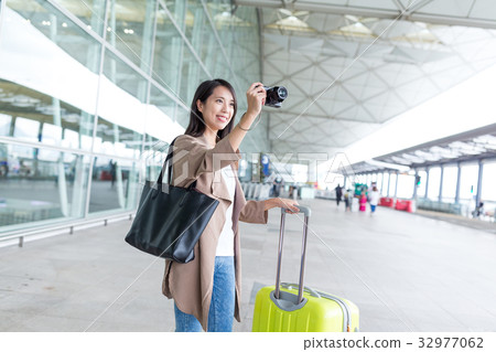 Woman taking photo by camera with her luggage in airport 32977062
