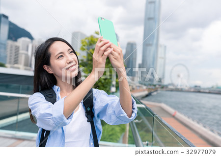 Woman taking photo on mobile phone in Hong Kong 32977079
